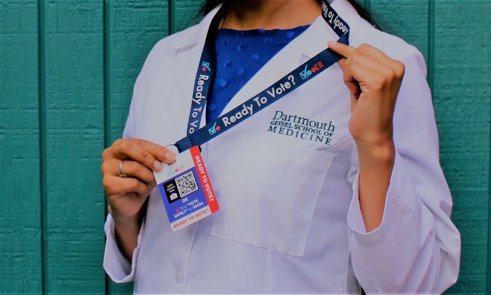 Dartmouth-medical-student-in-white-coat-wears-a-vot-er-badge